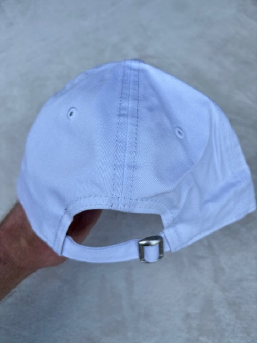 A white baseball cap viewed from the back, held by a hand against a gray textured background.